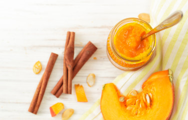 Pumpkin puree in a jar with cinnamon on white table