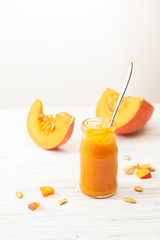 Pumpkin puree in a jar and chopped pumpkin on a white table