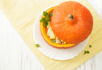 Closed pumpkin pot stuffed with vegetables on a white table