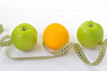 healthy eating, dieting, slimming and weigh loss concept - close up of green apple, banana, orange, juice, measuring tape.