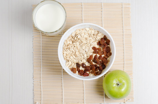 Oatmeal with raisins on the tablecloth from bamboo. Milk, green Apple