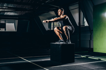 sportsman doing squats on cube
