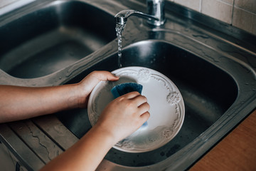 child washes the dishes