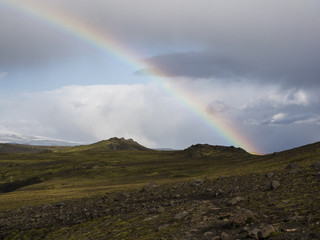 Rainbow over the mountains of Iceland, covered with green moss