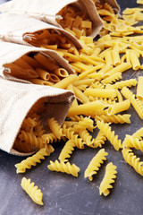 Various mix of pasta on grey rustic background. Diet and food concept