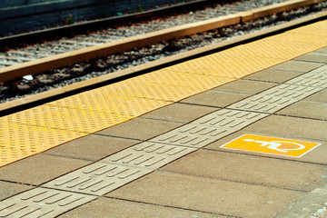 Train station platform with yellow tiles and handicap sign