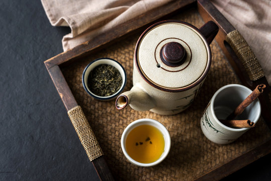 Tea set on wooden tray on black stone background