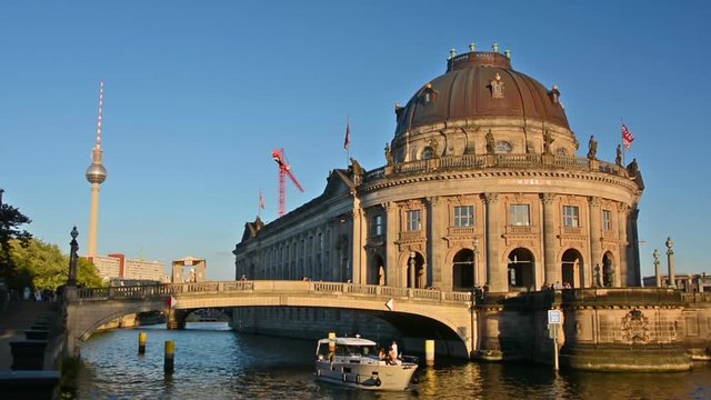 Boat cruises in front of the Bode Museum at sunset in Berlin.