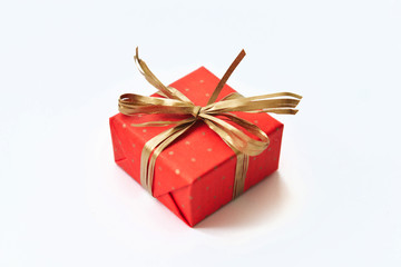 Red gift with golden bow on white background.