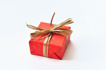 Red gift with golden bow on white background.
