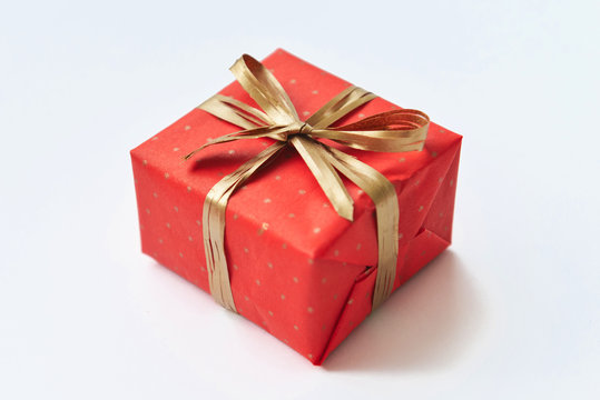 Red gift with golden bow on white background.