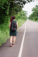 Happy Asian girl backpack in the road and forest background, Relax time on holiday concept travel