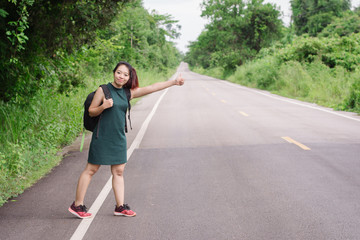 Happy Asian girl backpack in the road and forest background, Relax time on holiday concept travel