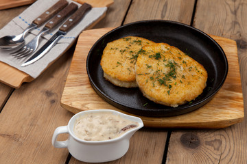 simple dish of Russian, Belarusian, Ukrainian cuisine on a old wooden boards, Potato pancakes in a frying pan on a table with sauce and cutlery