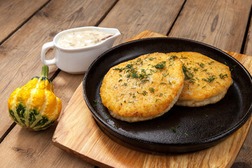 simple dish of Russian, Belarusian, Ukrainian cuisine on a old wooden boards, Potato pancakes in a frying pan on a table with sauce and cutlery