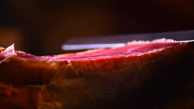 Jamon serrano. Slicing traditional spanish ham closeup. 4K UHD video 3840x2160 
