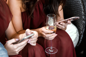 Young girl holding smartphone and pointing at party celebration, looking at screen and drinking champagne