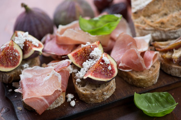 Close-up of bruschettas with prosciutto ham and ripe figs, selective focus