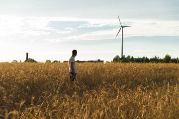 A man standing in a field looking at a wind generator