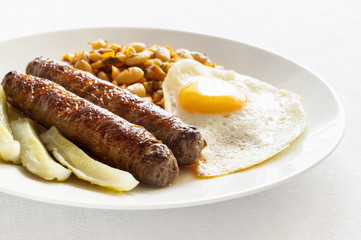 beef sausages, pickled cucumber, fried egg, and stewed beans