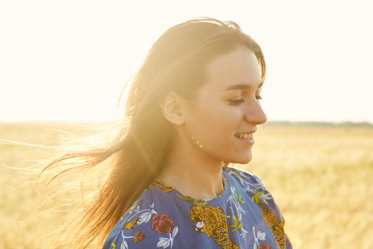 Portrait of a girl walking in the fields of wheat enjoying sunset