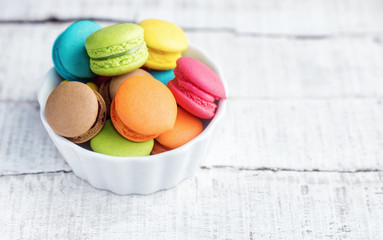 Vibrant colorfull macarons in plate on white wooden table. Text space