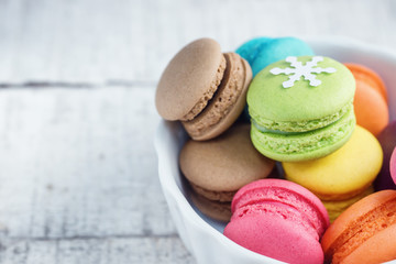 Vibrant colorfull macarons with christmas decoration on white wooden table. Text space