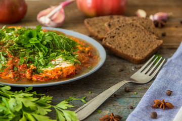 Shakshuka - jewish traditional recipe. Breakfast with fried eggs, tomato sause, pepper and green