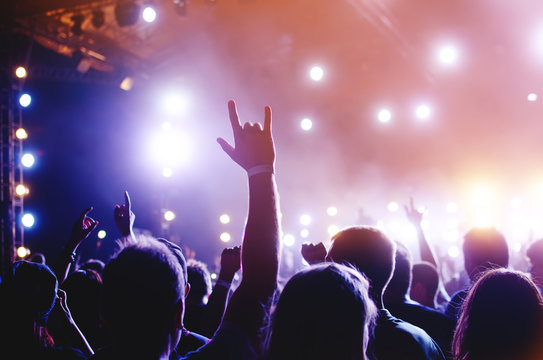 Silhouettes Of People In A Bright In The Pop Rock Concert In Front Of The Stage. Hands With Gesture Horns. That Rocks. Party In A Club