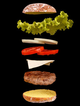 Burger parts flying in air isolated on black