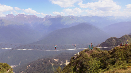 Obraz premium The crossing of the abyss in the mountains .People go on rope bridge across the chasm.