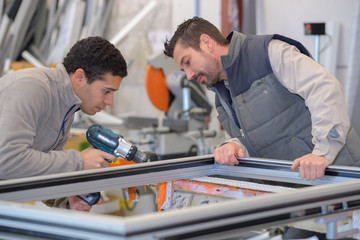 Worker using electric drill on window frame