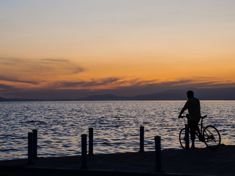 man standing at seaside with bicycle