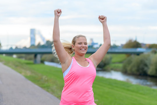 Young happy woman raising hands while running