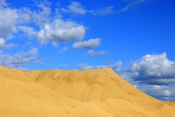 Fototapeta na wymiar Kopalnia odkrywkowa, góra piasku na tle błękitnego nieba.