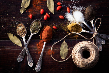 colorful spices in silver spoons on wooden table