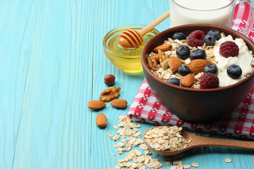 healthy breakfast. oatmeal, blueberries, raspberries, milk, honey and nuts on blue wooden table