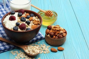 healthy breakfast. oatmeal, blueberries, raspberries, milk, honey and nuts on blue wooden table