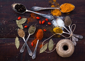 colorful spices in silver spoons on wooden table