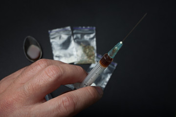 Syringe with a drug in his hand, close-up on a black background.