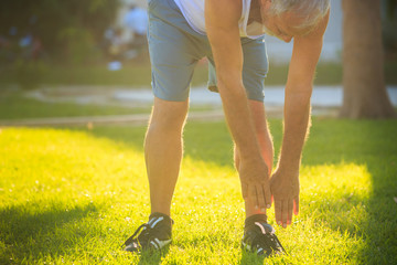 Legs of Man Doing Morning Exercises Touching Feet on Lawn