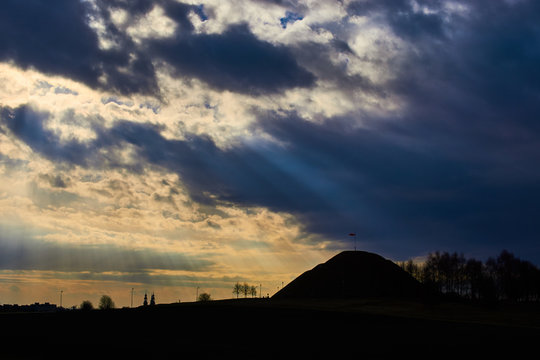 Promienie słoneczne padają przez chmury na kopiec, górę. Zdjęcie krajobrazowe HDR.