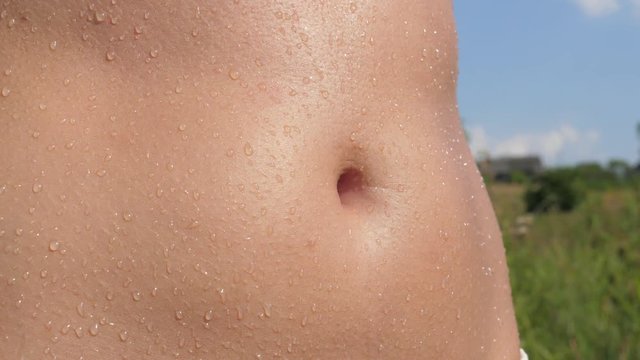 Closeup Of A Tanned Female Belly, Wet With The Droplets