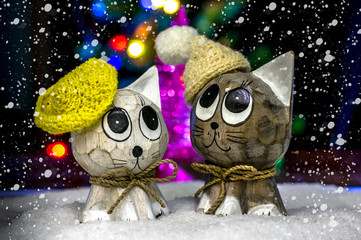 Two puppet cats in hats in the snow.