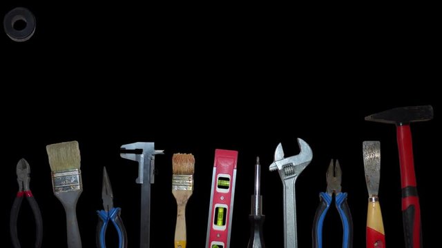 Different tools moving on black background. Hammer, screwdriver, pliers, brushes and over equipment fly from top of the screen to the bottom. Animation based on real photos. With alpha channel.