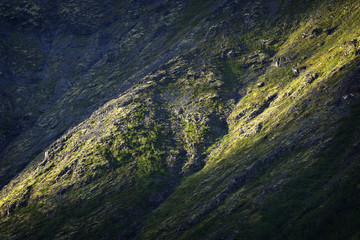 The mountain slope illuminated by the sun at sunset.