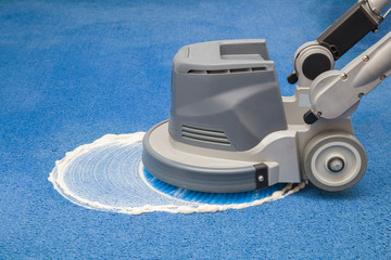 Blue carpet chemical foaming, rubbing and cleaning with professionally disk machine. Early spring regular cleanup. Cleaning service concept.