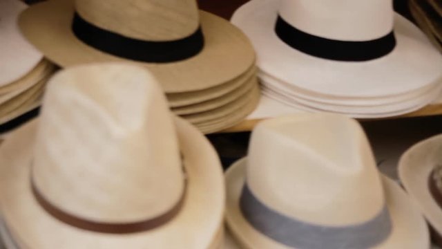 Hats for men (Panama) on sale at a public street market. Panning handheld shot.
