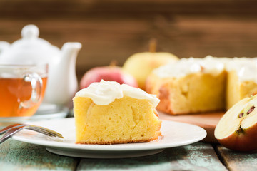 Traditional English apple cake with whipped cream served with tea and raw apples