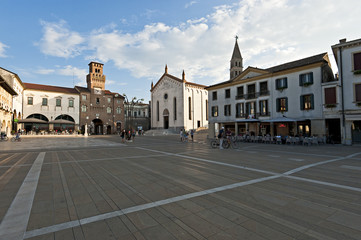 The clock tower or "Torresin" in Piazza Grande in Oderzo and the Cathedral. Ancient city of Roman origin in the province of Treviso, Italy.